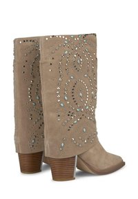 Stivali da cowgirl in suede beige con punta appuntita, decorati con borchie argento e blu in un motivo decorativo, dotati di un tacco in legno impilato.