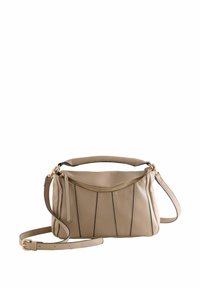 Bolso de mano de cuero beige con un diseño estructurado, que presenta acentos de costuras verticales, una cremallera superior y una correa de hombro desmontable.