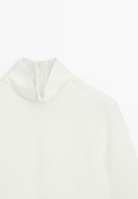 Bílý top s dlouhým rukávem, vysokým límcem a zapínáním na zip vzadu. Hladká textura a minimalistický design bez vzorů nebo doplňků.