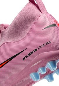 Różowy but sportowy z teksturowaną cholewką, z czarnymi akcentami, wyraźnym napisem 'AIR ZOOM' oraz niebieskimi kołkami zapewniającymi przyczepność na podeszwie.