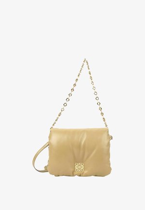 Sac à bandoulière en cuir beige avec bords festonnés, logo décoratif doré et une sangle en chaîne dorée.