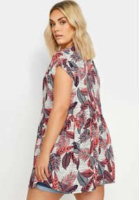 Túnica ligera de manga corta con un patrón floral en rojo, azul marino y blanco. Presenta una cintura fruncida y un corte relajado.