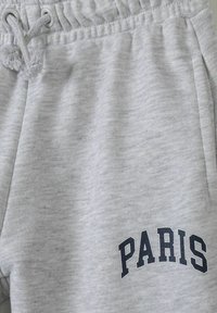 Grå sweatpants i mjukt tyg, med resårmidja och dragsko, samt "PARIS" tryckt i marinblått på benet.