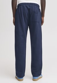 Mörkblå mjukisbyxor med elastisk midjeband, lös passform och en bakficka. Tillverkade av mjukt tyg med en slät yta.