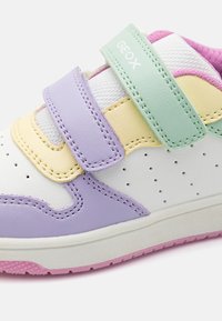 Λευκά sneakers με παστέλ λεπτομέρειες σε λιλά, κίτρινο και μέint πράσινο. Διαθέτουν δύο ιμάντες Velcro και τρυπητές λεπτομέρειες στο λευκό άνω μέρος.