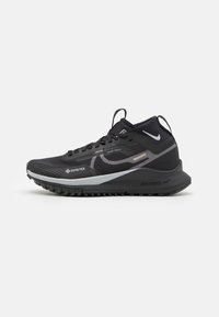 Zapatilla deportiva negra con parte superior texturizada, marca Gore-Tex, acentos reflectantes, suela acolchada y un diseño alto para soporte del tobillo.