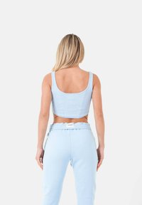 Top corto azzurro in tessuto a coste, dotato di spalline sottili e design aderente, abbinato a pantaloni della tuta azzurri dello stesso colore.