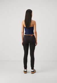 Donkerdenim strapless top, hooggetailleerde zwarte cargobroek met elastische boorden, en zwart-witte sneakers. Soepele textuur, op maat gemaakt ontwerp.