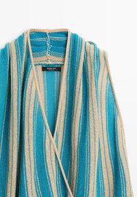 Blau-beiger gestreifter Strickcardigan mit tiefem V-Ausschnitt und sichtbarem Massimo Dutti Etikett im Kragen.