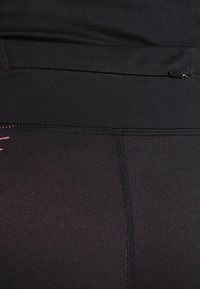 Leggings athletic neri realizzati in tessuto morbido, con una cintura larga, tasca nascosta e sottili dettagli rosa sul lato inferiore.