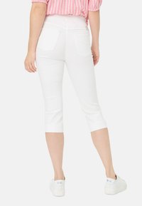 Witte, cropped leggings van een gladde stof, met een strakke pasvorm en een elastische tailleband. Voorzien van achterzakken en boorden aan de zoom. Gekocht in combinatie met witte sneakers.