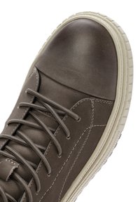 Bruine leren sneaker met een afgeronde, gladde neus, witte rubberen zool en opvallende veters. Heeft subtiele stikseldetails.