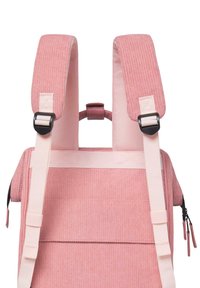 Zaino in corduroy rosa con spallacci regolabili, superficie testurizzata e spallacci a contrasto color crema. Anche i tiranti delle cerniere sono rosa, arricchendo il design.