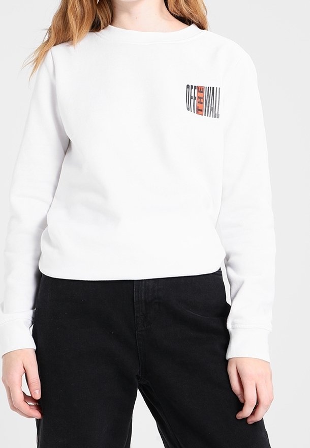 Vit sweatshirt med rund halsringning och långa ärmar. Har en liten svart och röd grafisk text "OFF THE WALL" på vänster bröst.