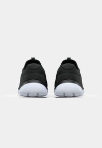 Scarpe sportive nere con tomaia testurizzata, punta arrotondata e suola in gomma bianca. Presentano un tassello sul tallone per facilitare l'indossamento.