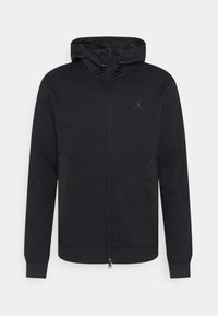 Sweat à capuche zippé noir en tissu doux, avec une poche kangourou, une capuche à cordon et un logo discret sur la poitrine.