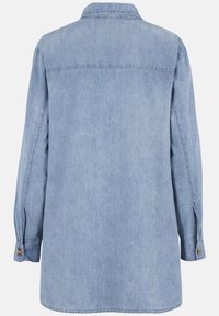 Camicia di jeans a maniche lunghe blu chiaro con polsini abbottonati vista da dietro su uno sfondo bianco.