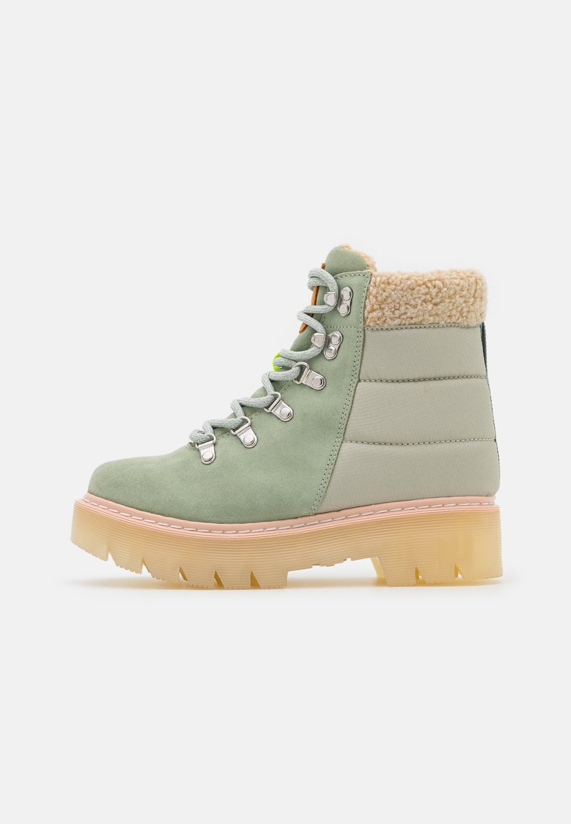 Botte d’hiver en daim vert avec col en polaire beige, crochets métalliques pour les lacets, dos en tissu rembourré et semelle en caoutchouc épaisse translucide.