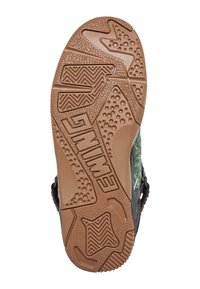 Koripallon kengän pohja, jossa on kuminen pinta, zigzag-kuvioinen pito, ympyrän muotoiset kivipisteet ja keskellä kaiverrettu brändin logo.