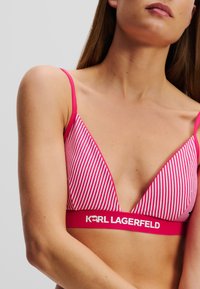 Rosa och vitrandig triangelformad bralette med tunna band; har en solid rosa elastisk kant med "KARL LAGERFELD"-logotyp nederst.