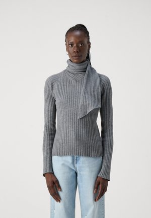 Pull à col montant gris à côtes avec un décolleté drapé et des manches longues. Assorti à un jean bleu clair, au fit décontracté.