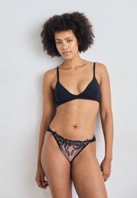 Black lingerie set featuring a triangle bralette with adjustable straps and a sheer thong with floral embroidery and scalloped edges.