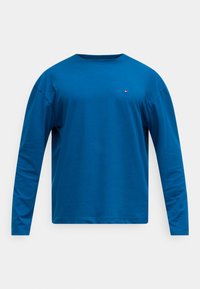 Μπλε βαμβακερό μπλουζάκι μακρυμάνικο με στρογγυλή λαιμόκοψη και μικρό κόκκινο και λευκό λογότυπο στο αριστερό στήθος. Λεία υφή, casual σχεδιασμός.