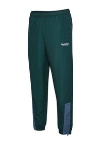 Grüne Sporthose aus glattem Material. Verfügt über einen elastischen Bund, Seitentaschen und graue Akzente am Saum. Hummel-Logo sichtbar.