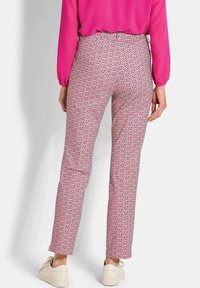 Roze gemusterde broek met een geometrisch ontwerp, voorzien van een rechte snit, zachte stof en subtiele accenten, gecombineerd met witte sneakers.