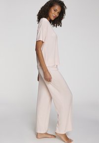 Lichtroze loungewear-set met een geribbelde top met korte mouwen en een wijde broek, gemaakt van een zachte, gestructureerde stof voor comfort.