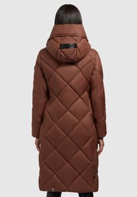 Brūns izolēts garais mētelis ar izšūtu dimanta rakstu, kapuci un melnu logotipa birku. Gluda tekstūra un pieguļošs siluets.