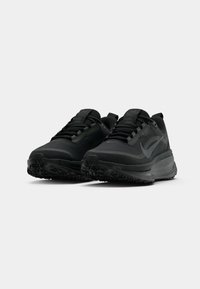 Un paio di scarpe da corsa nere Nike con suole texture e design con lacci, mostrate da un'angolazione bassa anteriore su sfondo bianco.
