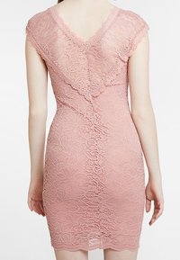 Robe en dentelle rose avec des manches courtes et un dos en V, ornée de motifs floraux et d'une coupe ajustée qui souligne la silhouette.