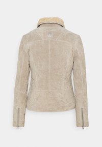 Beige suède jas met schapenvachtkraag, stiksel op het achterpaneel en ritssluitingen op de mouwboorden.