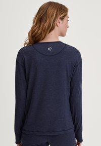 Marineblauw langarmshirt van zachte stof, met een ronde halslijn en een klein logo op de middenachter; ontspannen pasvorm.