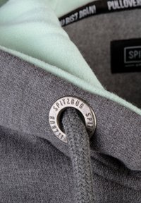 Grauer Pullover mit mintgrünem Innenfutter und einem Metall-Ösen. Verfügt über eine Strickstruktur und eine Zugkordel. Logo innen sichtbar.