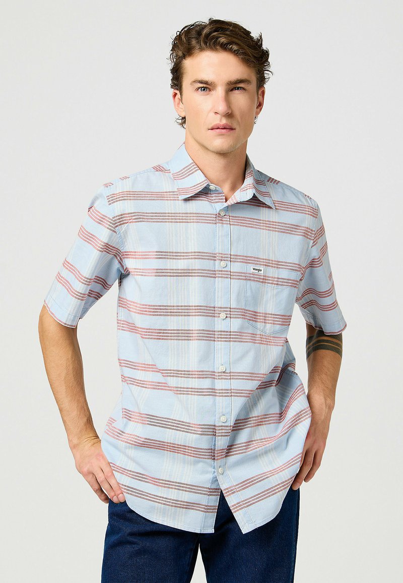 Camicia a maniche corte con bottoni di colore azzurro chiaro, con un motivo a quadri rosso e crema. Presenta una tasca sul petto e una vestibilità comoda.