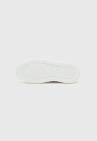 White sneaker sole with textured rubber, featuring horizontal and vertical ribbing patterns for traction, smooth edges, and a rounded shape.