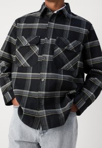 Schwarz-weißer karierthemd mit zwei Brusttaschen, aus weichem Stoff gefertigt. Verfügt über einen klassischen Kragen und lange Ärmel.