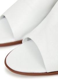Weiße Leder-Slide-Sandalen mit offener Zehe und runder Form. Sie zeichnen sich durch eine glatte Textur und eine kontrastierende braune Sohle aus.