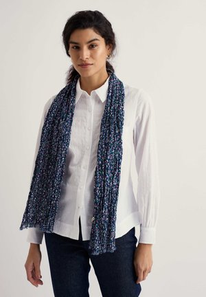 Marineblauer Schal mit strukturiertem, plissiertem Design und Blumenmustern in Violett-, Weiß- und Grüntönen, getragen über einem weißen Hemd.