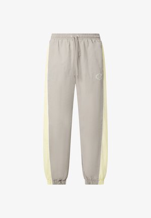 Pantalon de jogging gris clair avec bandes latérales jaune pâle, poignets et ceinture élastiques, cordon de serrage et petit logo sur la cuisse gauche.