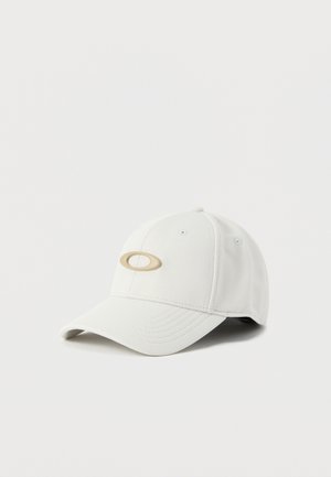 Casquette de baseball blanche avec un logo ovale beige à l'avant, présentée sur un fond clair uni.