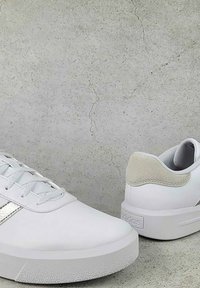 Sneakers bianchi con finitura in pelle liscia, suola in gomma testurizzata e accentuazione in suede sul tallone. Presentano lacci e strisce argentate sui lati.
