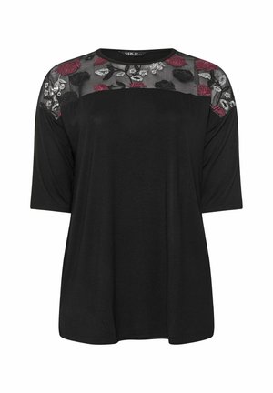 Haut noir avec des manches trois-quarts, encolure en dentelle florale noire transparente et coupe décontractée. Présente des motifs de roses et de feuilles en bourgogne et blanc.