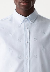 Camicia azzurro chiaro con un motivo ricamato del logo dei New York Yankees, con colletto classico e chiusura a bottoni.