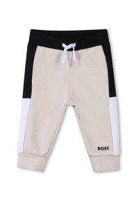 Pantalons de jogging beige clair avec des panneaux latéraux noir et blanc, taille élastique avec cordon de serrage, poignets côtelés et logo "BOSS" noir sur la jambe.