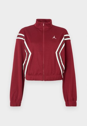 Burgunderrote, kurze Jacke mit durchgehendem Reißverschluss und hohem Kragen, weißen und schwarzen schrägen Streifen auf der Vorderseite und den Ärmeln sowie kleinem weißen Logo auf der Brust.