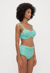 Turquoise bikini set featuring a textured, sparkly bralette with adjustable straps and high-waisted bottom with a belt detail.