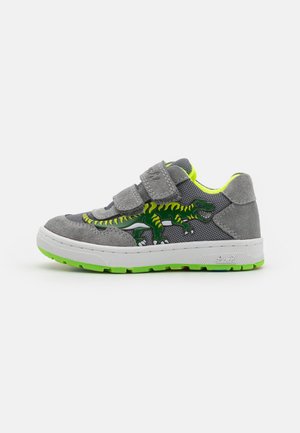 Graue Wildleder-Sneaker mit Mesh-Seiten, grünem Dinosaurier-Graphic, doppelten Klettverschlüssen und einer weißen Sohle mit grünen Akzenten.